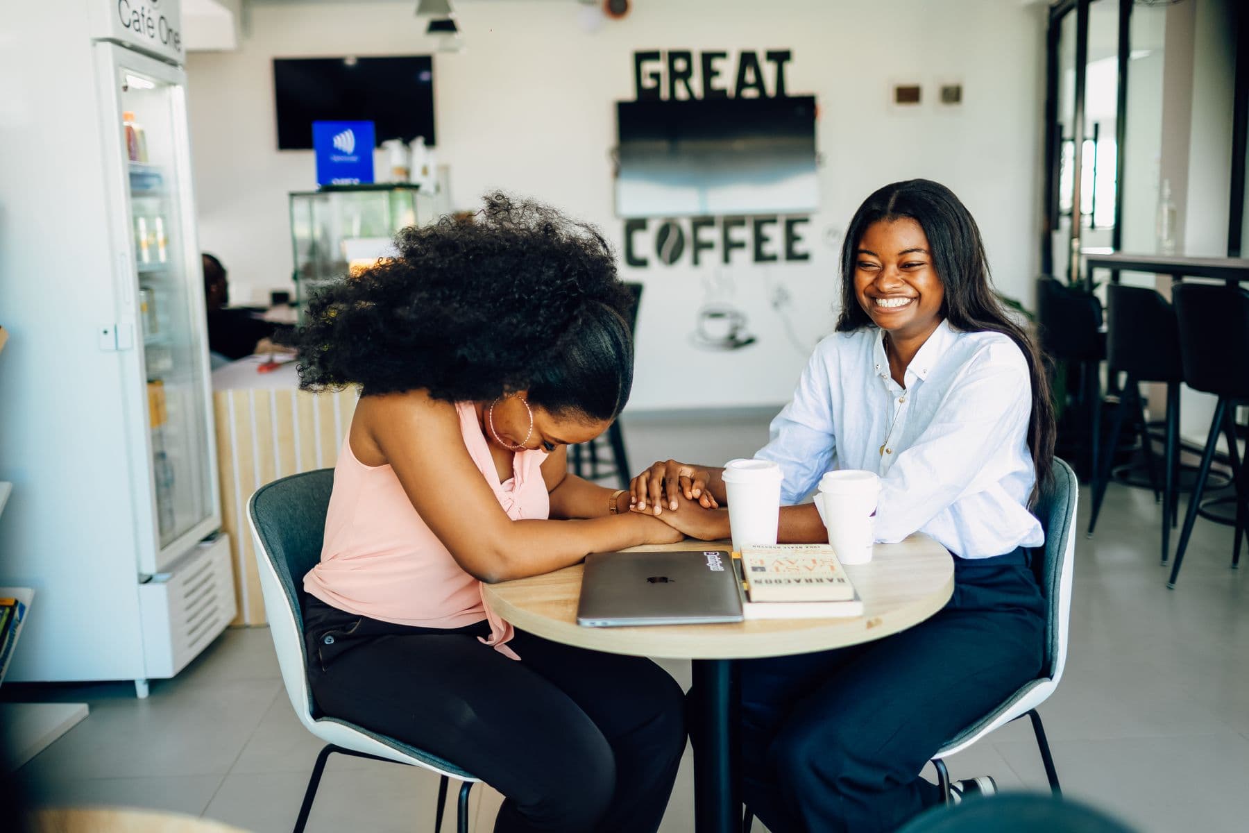 Two friends at a café table planning a birthday wish