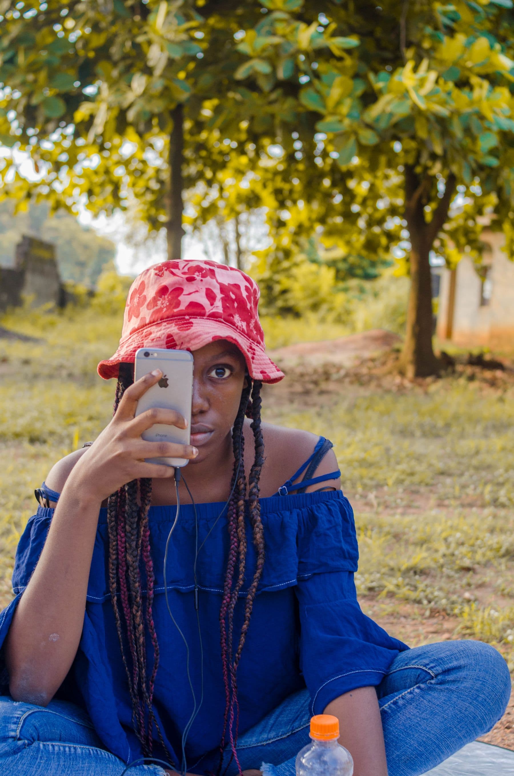 Young woman in a red bucket hat holding up her phone